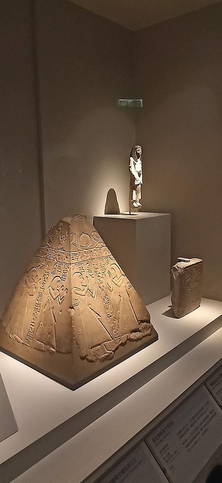 展櫃一景:金字塔頂石、內布拉雕像與石碑。