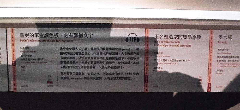 說明牌:書吏的筆盒調色板,刻有葬儀文字(第十八王朝,片岩,EA12779;雙墨槽分裝紅黑墨水)。