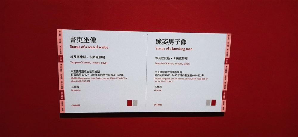 說明牌:書吏坐像(石英岩,EA48032)與跪姿男子像(花崗岩,EA48036),皆出自卡納克神廟。