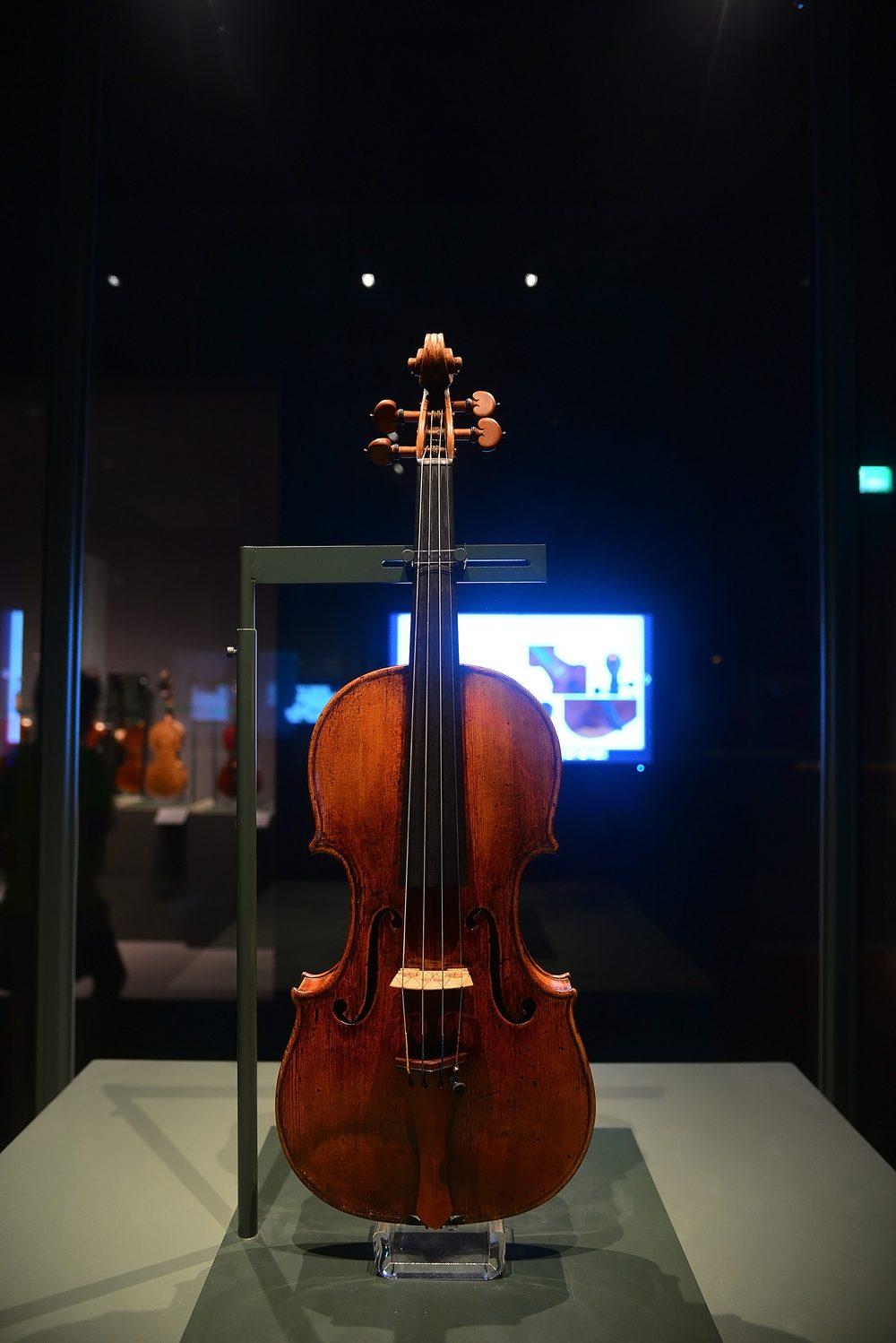 瓜奈里.耶穌 1733 年小提琴正面全貌,直立於玻璃展櫃中,背景為提琴廳其他展品。