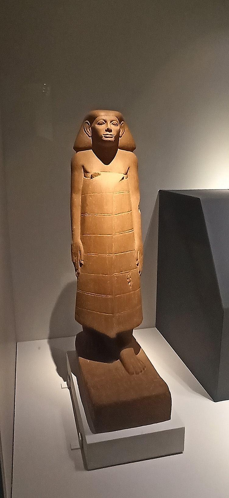 立像正面近照,裹身長裙為當時流行的男士衣著。