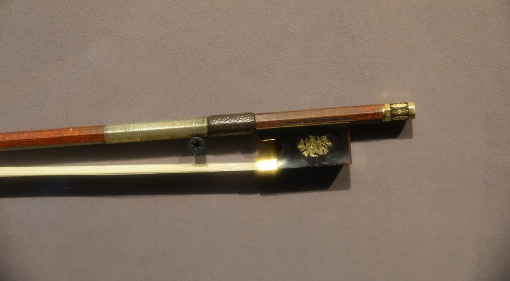 紐倫堡二世小提琴弓弓尾特寫,弓桿「ALBERT NURNBERGER」烙印可辨,玳瑁馬尾庫飾金色花卉紋——此弓曾為克萊斯勒所用。