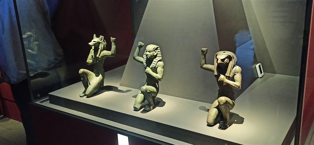三尊跪姿小雕像:胡狼首的阿努比斯、法老與隼首的荷魯斯,皆單臂上舉。